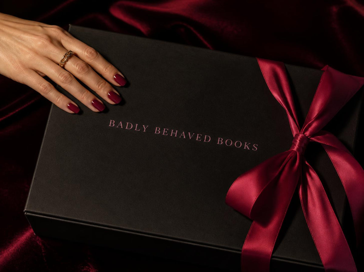 An open spicy romance book on silk sheets beside a candle and cherries